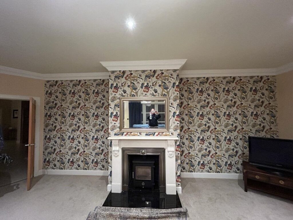 Completed living room wallpapering with patterned wallpaper fitted neatly around the fireplace and chimney breast.